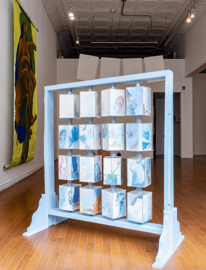 Levin's art piece "Ultimatum, Baby!" showing in Stride Gallery. It is a blue wooden structure and has picture blocks you can spin.